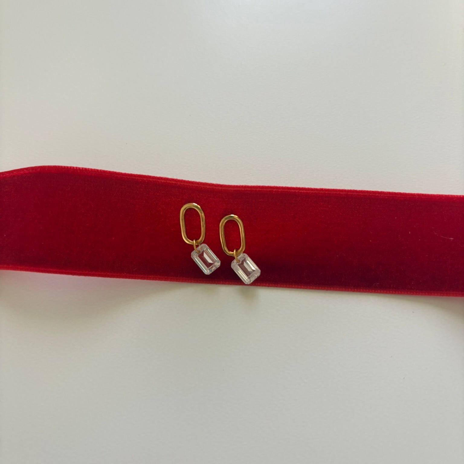 Pair of earrings on a red cushion with a white background